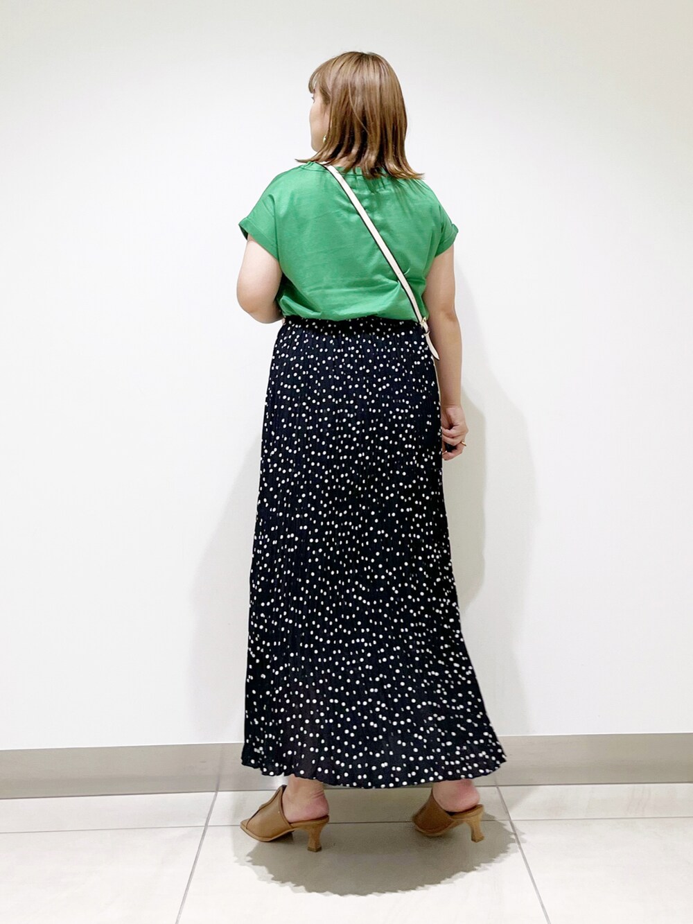 グリーン系のTシャツ/カットソー、ブラック系のスカート、ベージュ系のサンダルを着用したレディースの夏コーディネートの5枚目の写真