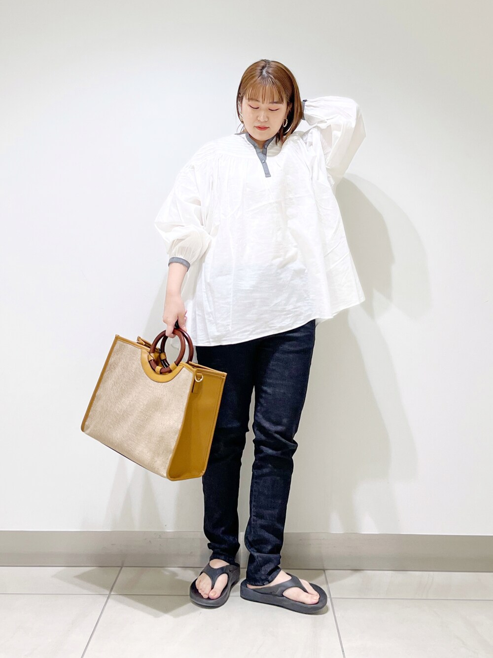 ホワイト系のシャツ/ブラウス、イエロー系のトートバッグ、ブラック系のデニムパンツを着用したレディースの春コーディネートの5枚目の写真