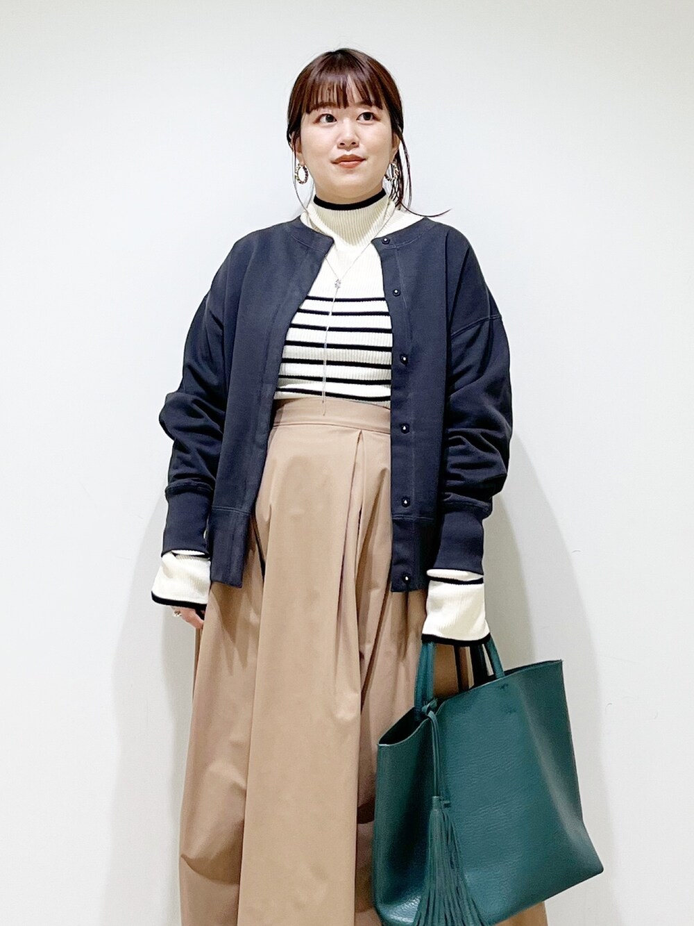 グリーン系のトートバッグ、ベージュ系のスカート、その他のバレエシューズを着用したレディースの秋コーディネートの4枚目の写真