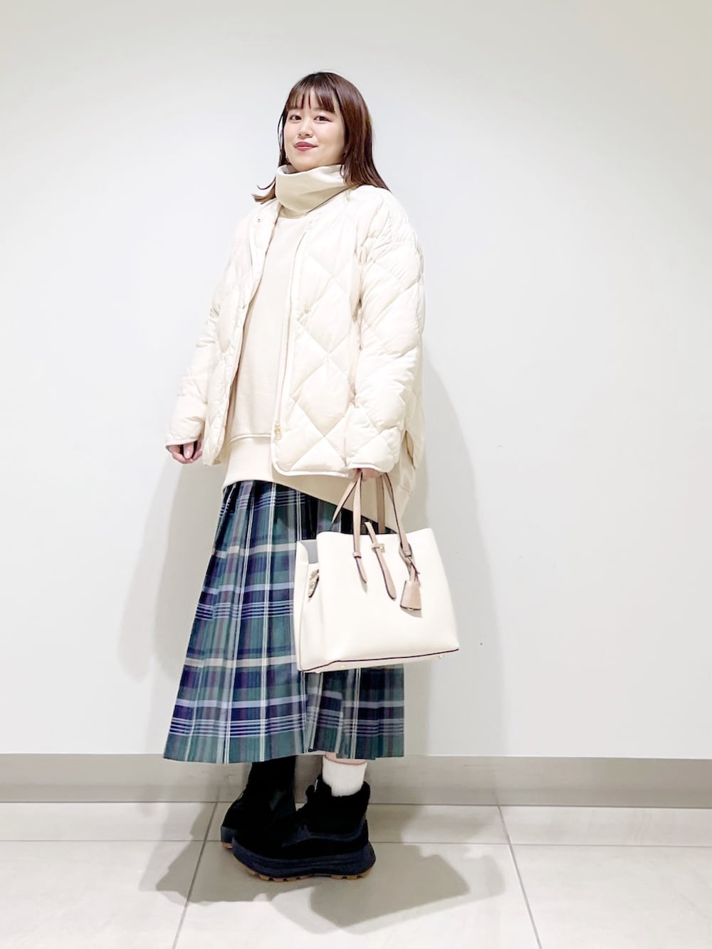ベージュ系のスウェット、ホワイト系のダウンジャケット/コート、グリーン系のスカートを着用したレディースの秋コーディネートの3枚目の写真