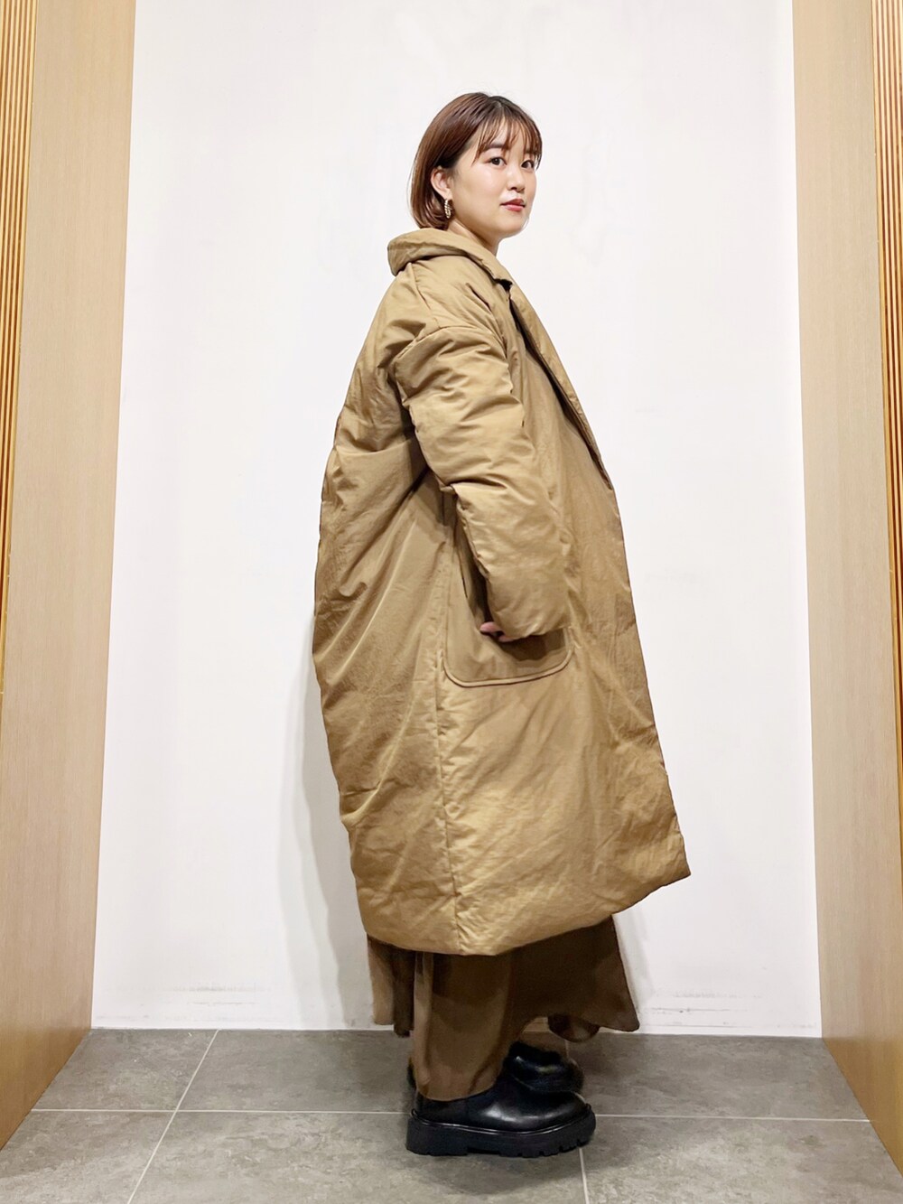 ベージュ系のダウンジャケット/コート、ブラウン系のワンピース、ホワイト系のニット/セーターを着用したレディースの秋コーディネートの4枚目の写真