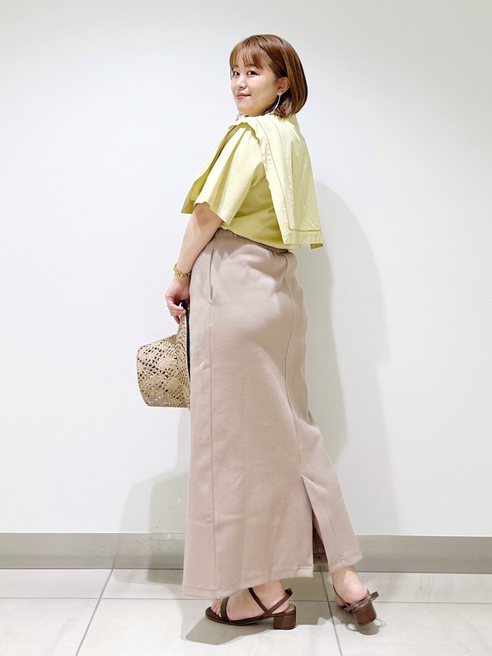 イエロー系のシャツ/ブラウス、ブラウン系のサンダル、ベージュ系のスカートを着用したレディースの夏コーディネートの2枚目の写真
