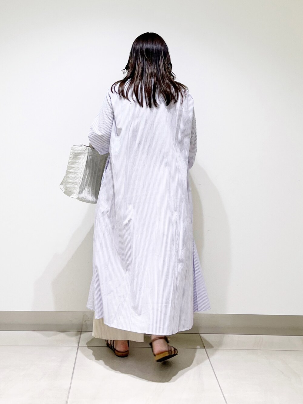 ベージュ系のTシャツ/カットソー、ベージュ系のスカート、パープル系のワンピースを着用したレディースの春コーディネートの4枚目の写真