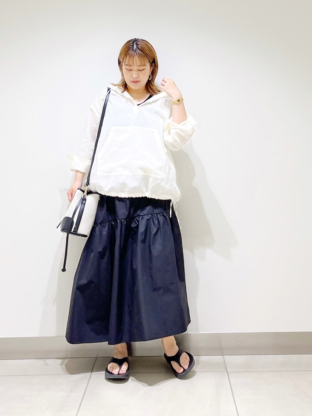 ホワイト系のパーカー、ブラック系のスカート、ブラック系のショルダーバッグを着用したレディースの夏コーディネートの3枚目の写真