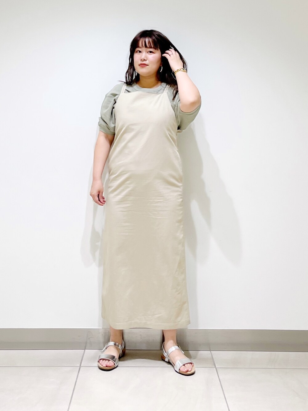 ベージュ系のワンピース、シルバー系のサンダル、グリーン系のTシャツ/カットソーを着用したレディースの春コーディネートの6枚目の写真