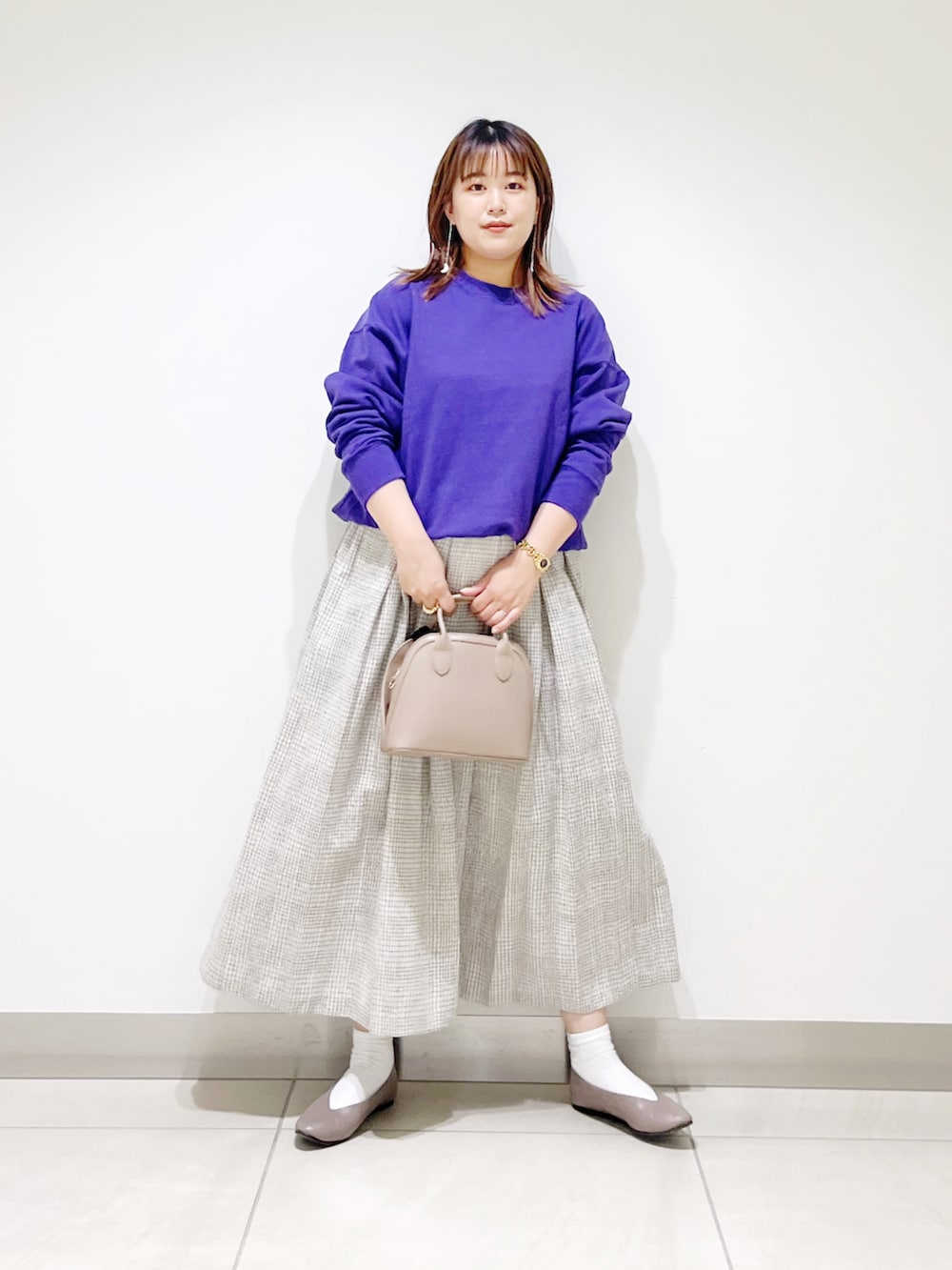 パープル系のスウェット、ホワイト系のスカート、ベージュ系のショルダーバッグを着用したレディースの秋コーディネートの2枚目の写真