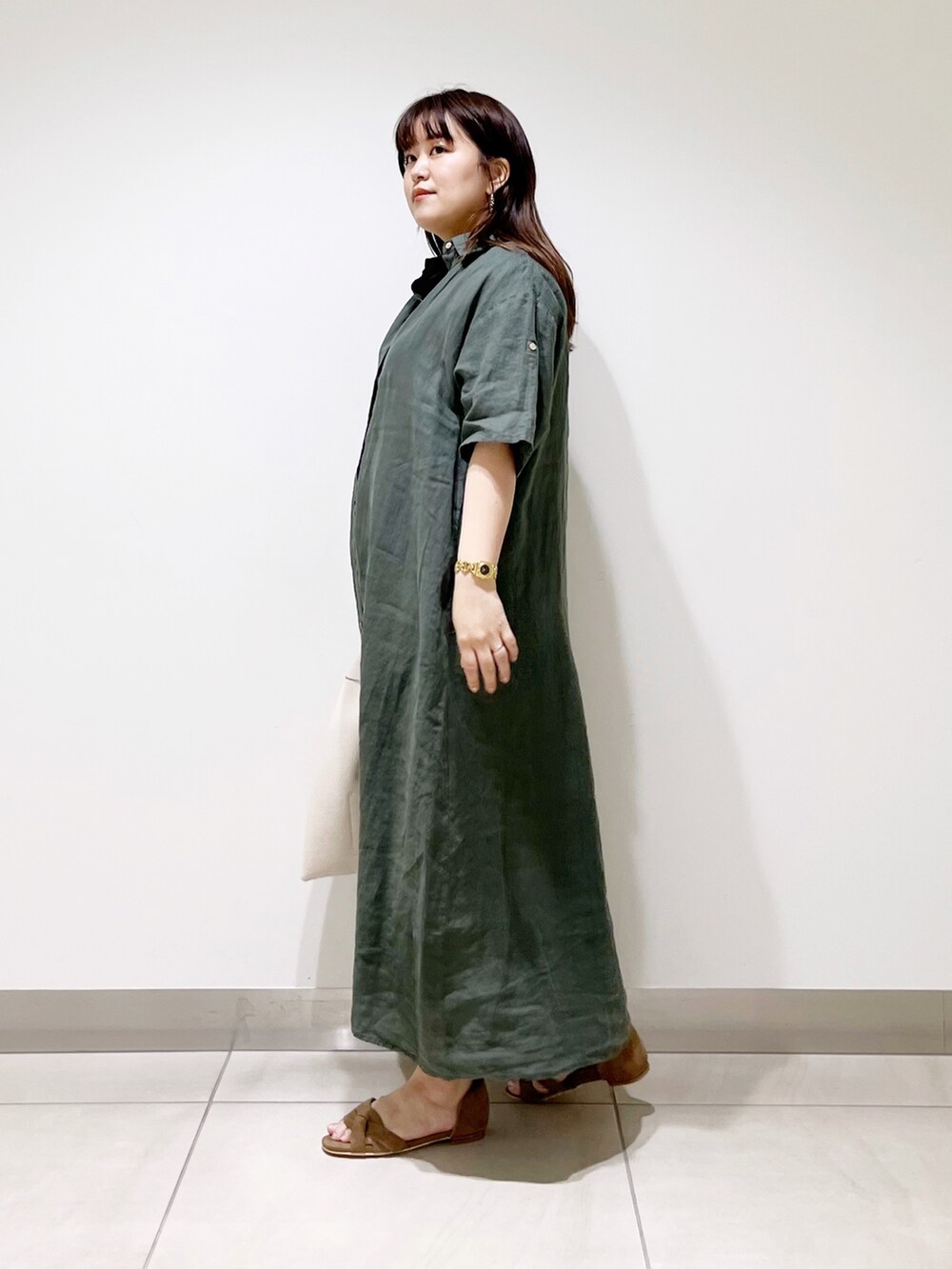 グリーン系のワンピース、ホワイト系のトートバッグ、ベージュ系のサンダルを着用したレディースの春コーディネートの5枚目の写真