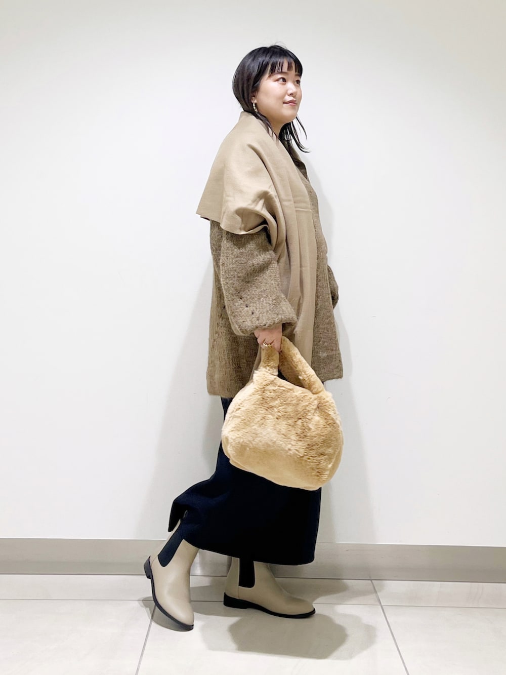 ブラウン系のニット/セーター、イエロー系のハンドバッグ、ブラック系のスカートを着用したレディースの冬コーディネートの4枚目の写真