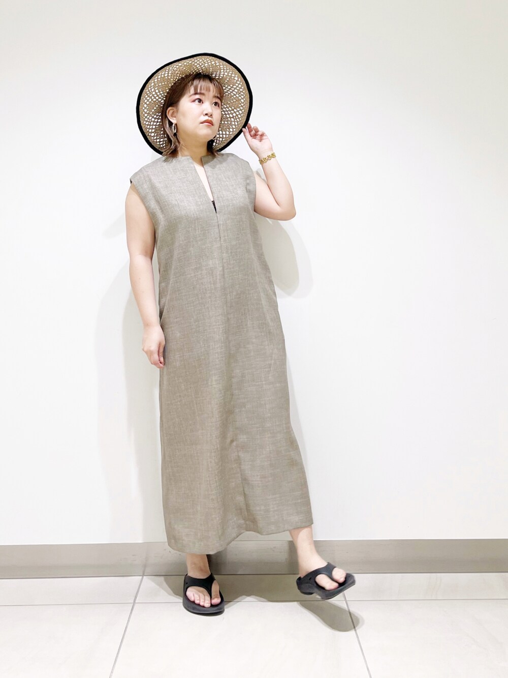 グレー系のワンピース、ブラック系のサンダル、ブラック系のハットを着用したレディースの春コーディネートの3枚目の写真