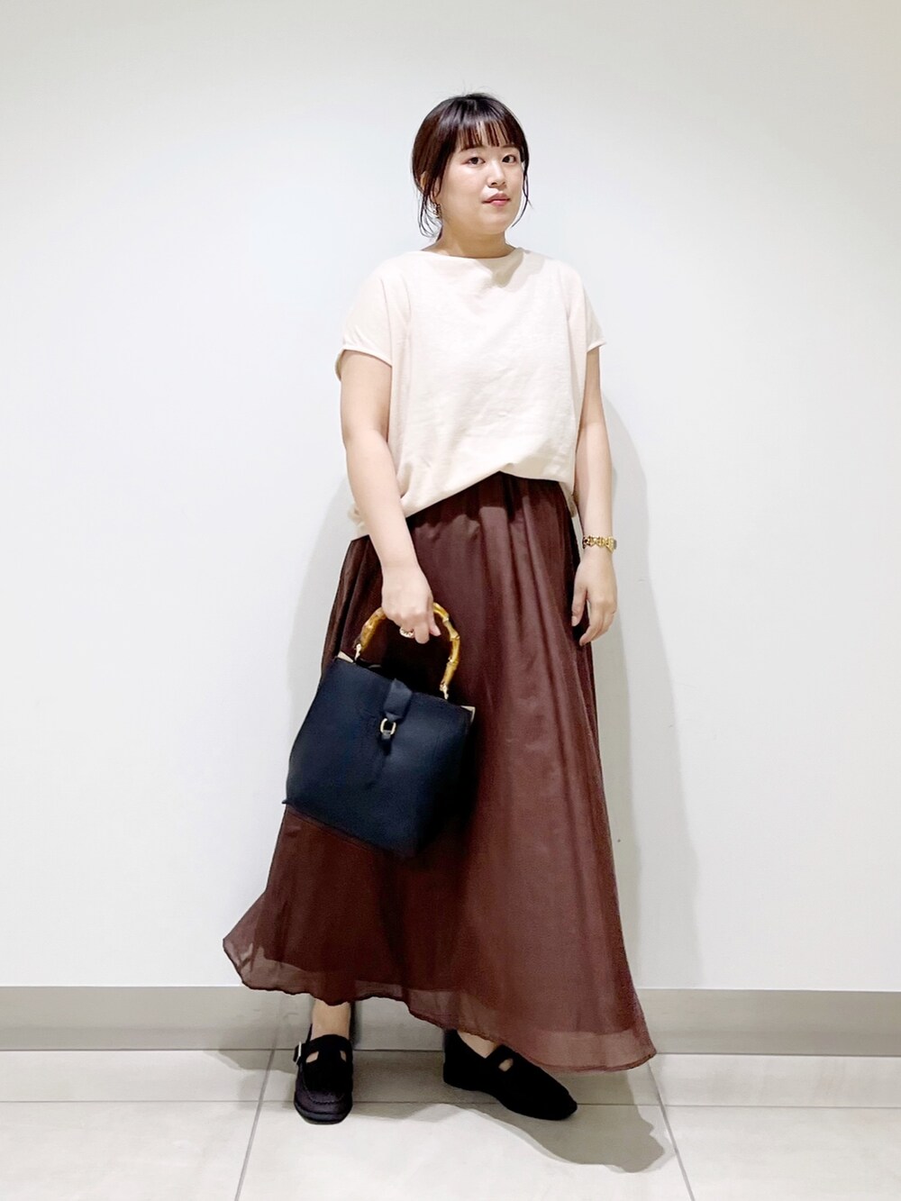 ベージュ系のTシャツ/カットソー、ブラウン系のスカート、ブラック系のハンドバッグを着用したレディースの夏コーディネートの7枚目の写真