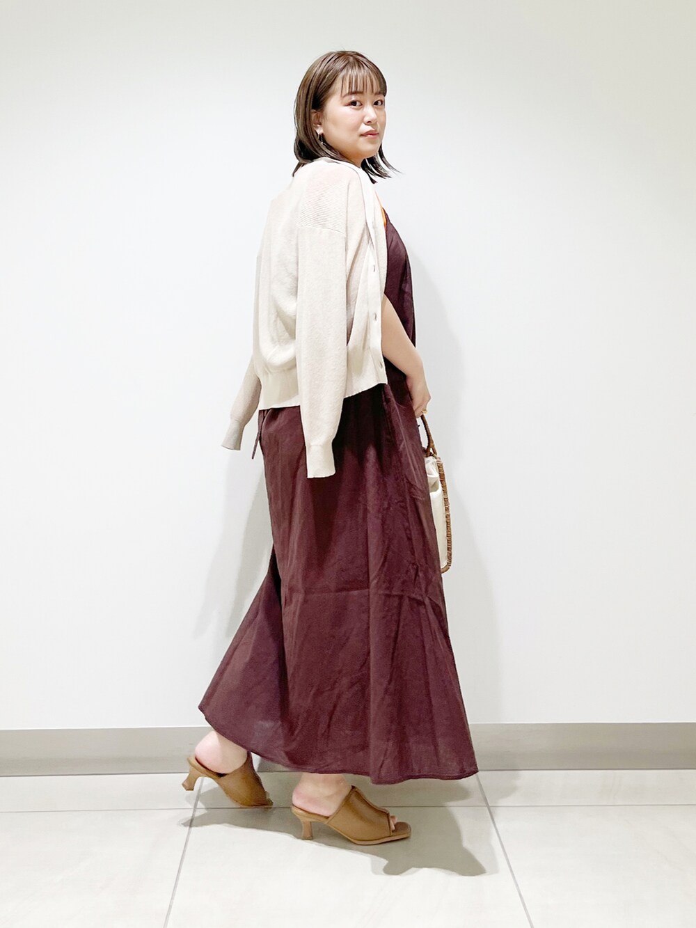 ブラウン系のワンピース、オレンジ系のニット/セーター、ホワイト系のハンドバッグを着用したレディースの春コーディネートの4枚目の写真