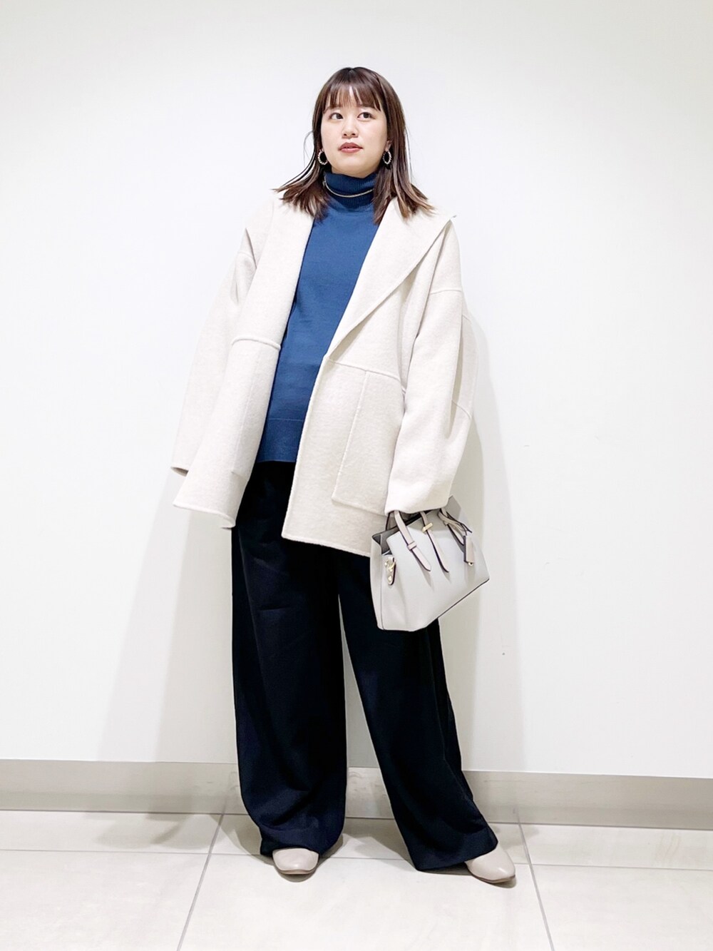 ベージュ系のその他アウター、ブルー系のニット/セーター、ブラック系のパンプスを着用したレディースの冬コーディネートの8枚目の写真