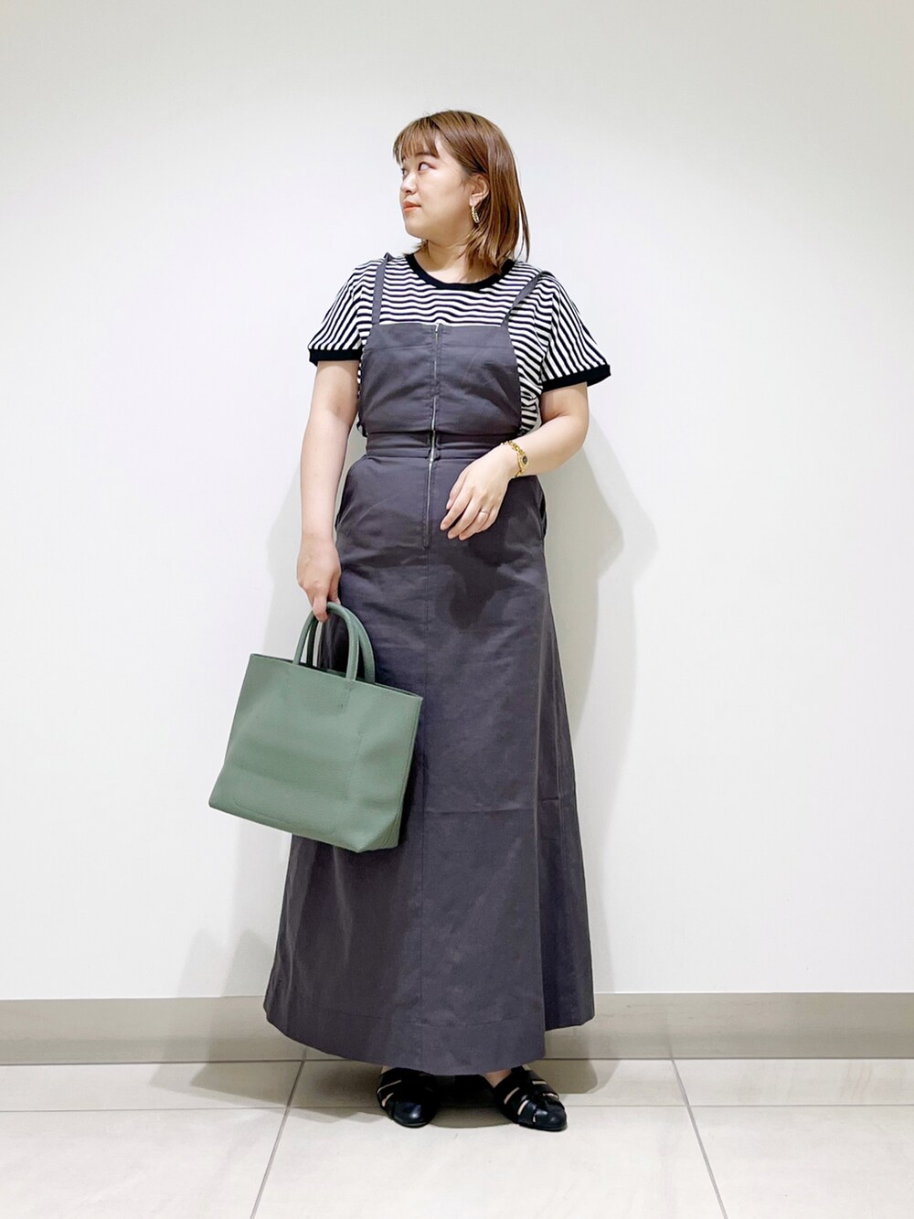 グレー系のワンピース、グリーン系のトートバッグ、ブラック系のサンダルを着用したレディースの春コーディネートの2枚目の写真