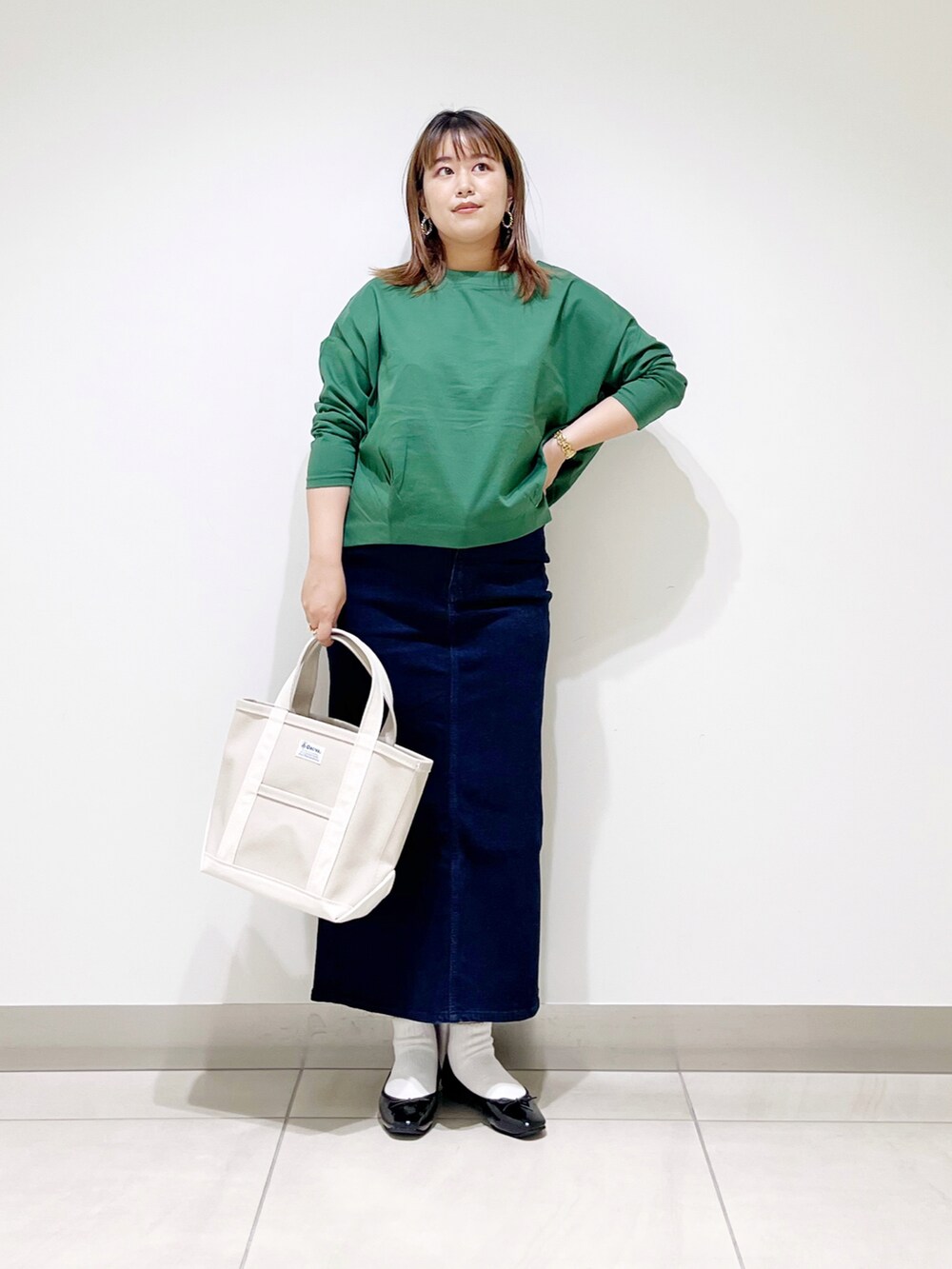 グリーン系のTシャツ/カットソー、ブルー系のスカート、ホワイト系のトートバッグを着用したレディースの秋コーディネートの2枚目の写真