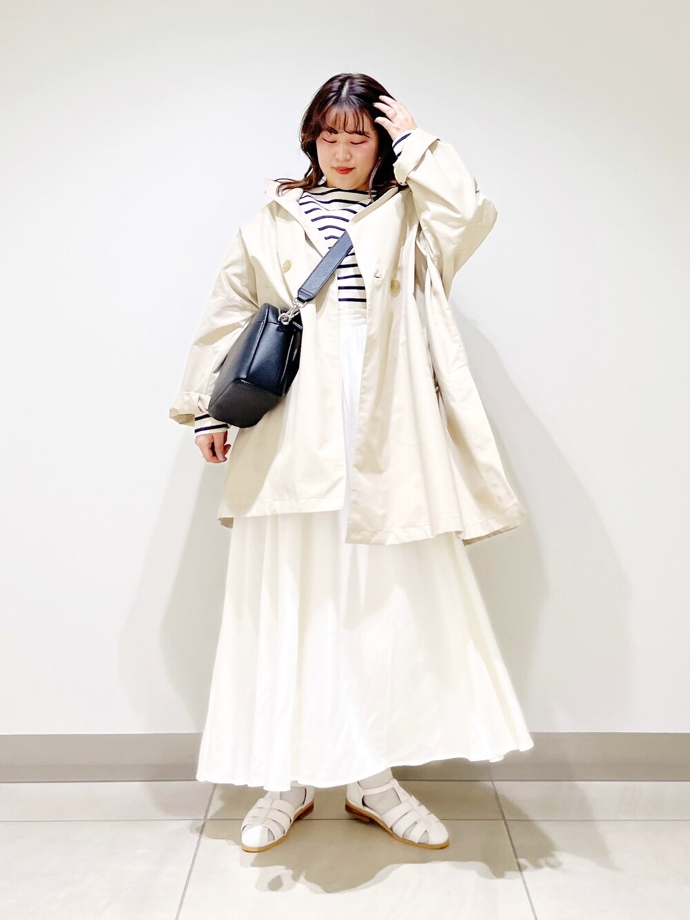 ベージュ系のポンチョ、ホワイト系のTシャツ/カットソー、ホワイト系のスカートを着用したレディースの春コーディネートの2枚目の写真