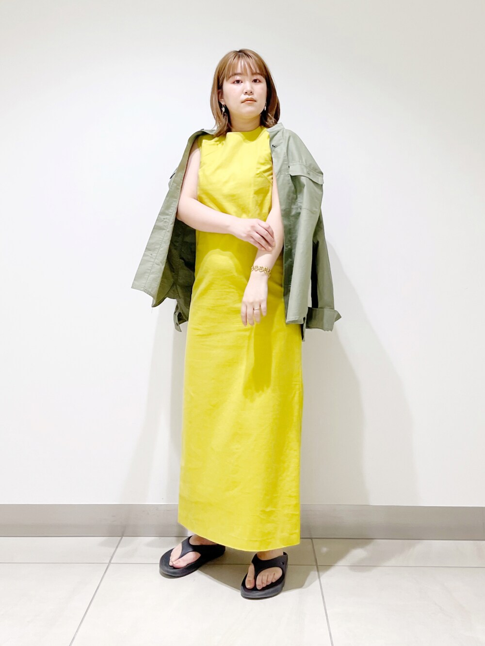 イエロー系のワンピース、グリーン系のシャツ/ブラウス、ブラック系のサンダルを着用したレディースの春コーディネートの5枚目の写真