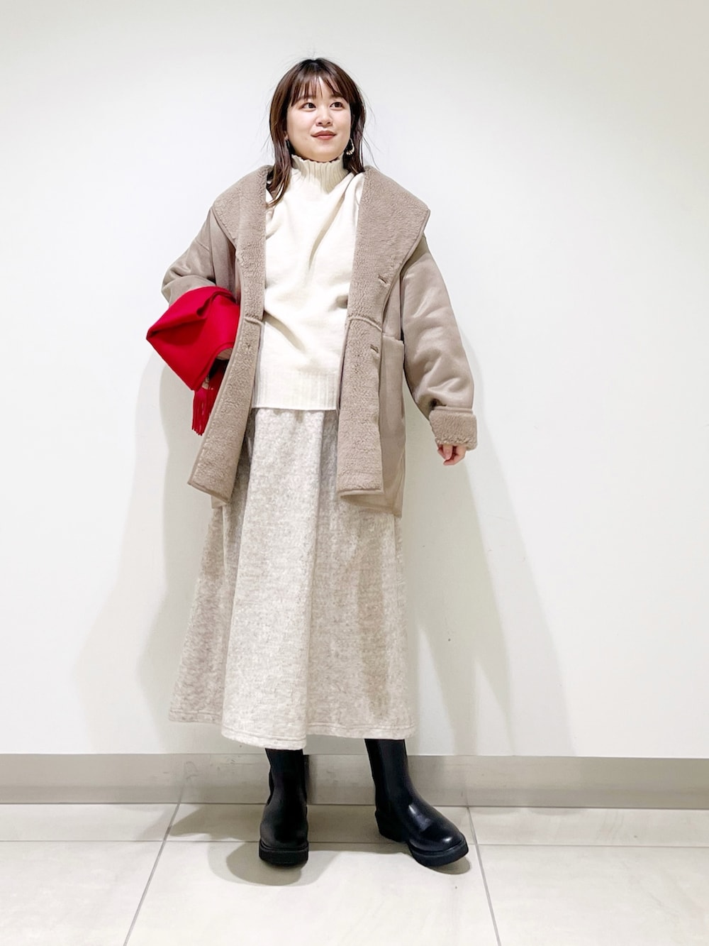 グレー系のムートンコート、ホワイト系のニット/セーター、ベージュ系のスカートを着用したレディースの冬コーディネートの3枚目の写真