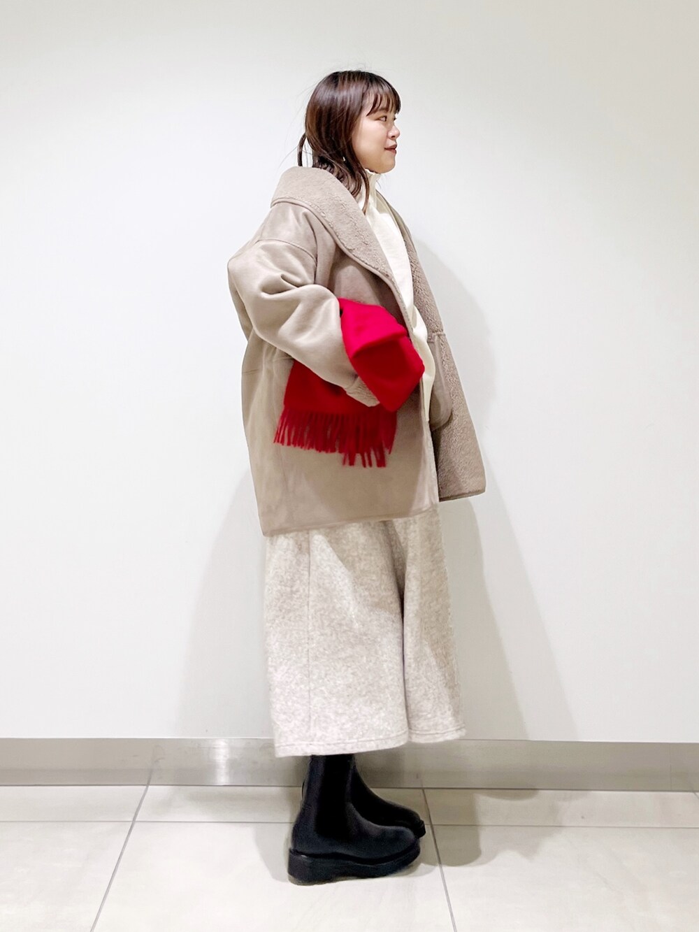 グレー系のムートンコート、ホワイト系のニット/セーター、ベージュ系のスカートを着用したレディースの冬コーディネートの7枚目の写真
