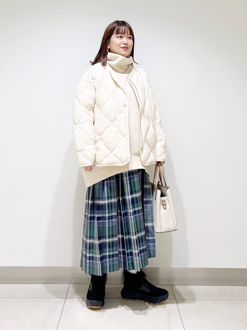 ベージュ系のスウェット、ホワイト系のダウンジャケット/コート、グリーン系のスカートを着用したレディースの秋コーディネートの8枚目の写真
