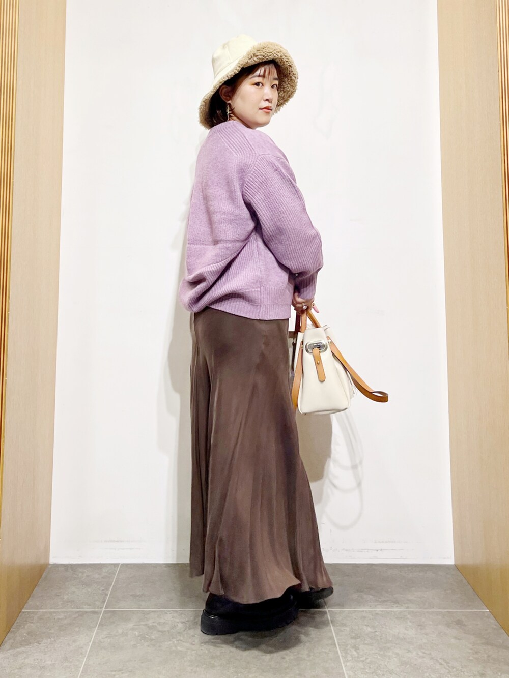 パープル系のニット/セーター、ブラウン系のスカート、ホワイト系のトートバッグを着用したレディースの冬コーディネートの5枚目の写真