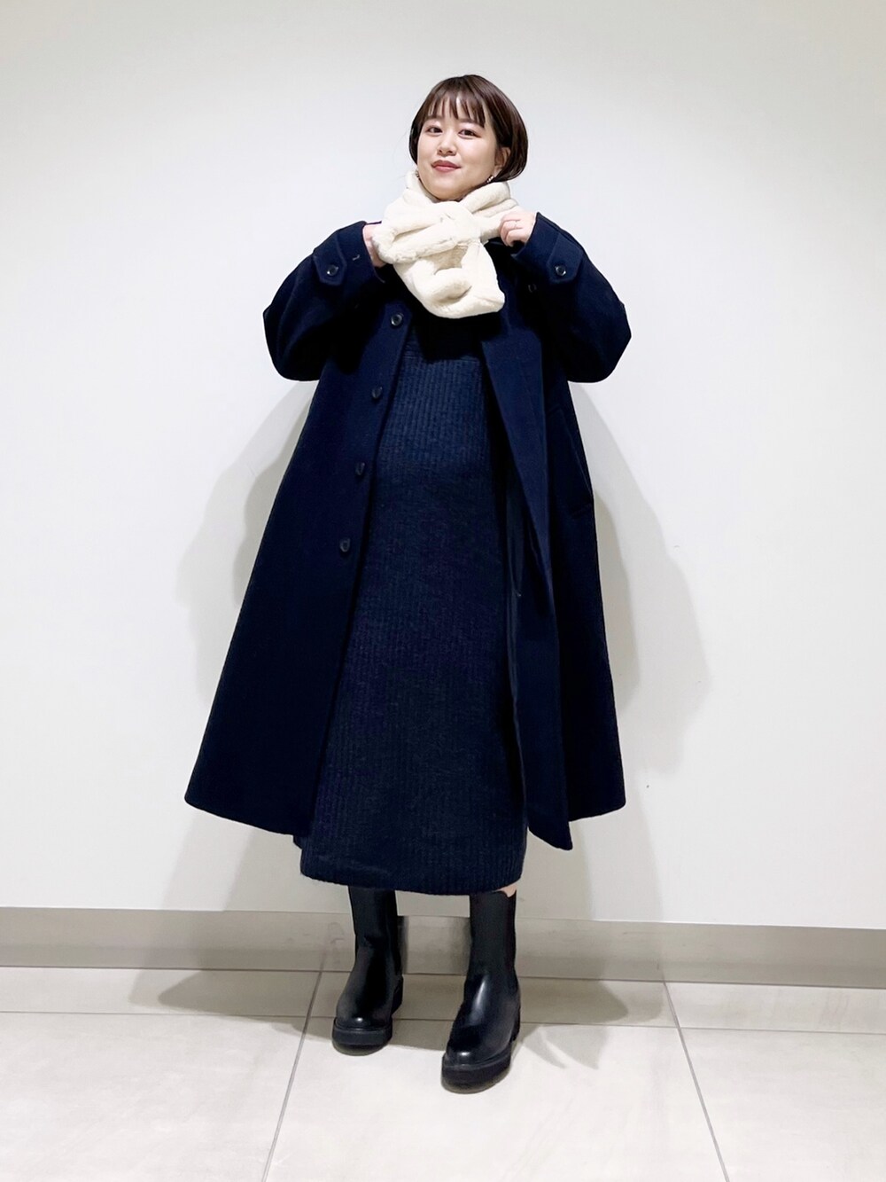 ブルー系のステンカラーコート、ブルー系のワンピース、ブラック系のブーツを着用したレディースの冬コーディネートの4枚目の写真