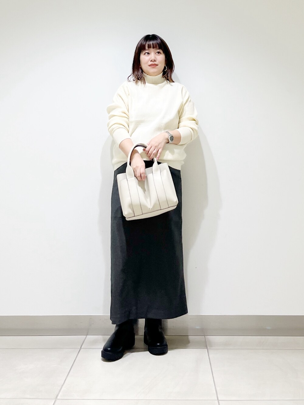ホワイト系のニット/セーター、ホワイト系のトートバッグ、グレー系のスカートを着用したレディースの秋コーディネートの9枚目の写真