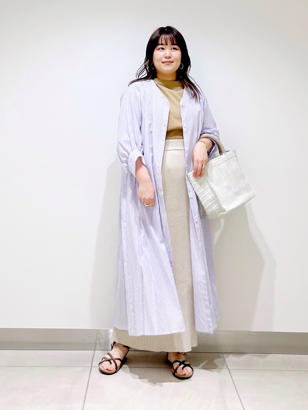 ベージュ系のTシャツ/カットソー、ベージュ系のスカート、パープル系のワンピースを着用したレディースの春コーディネートの2枚目の写真