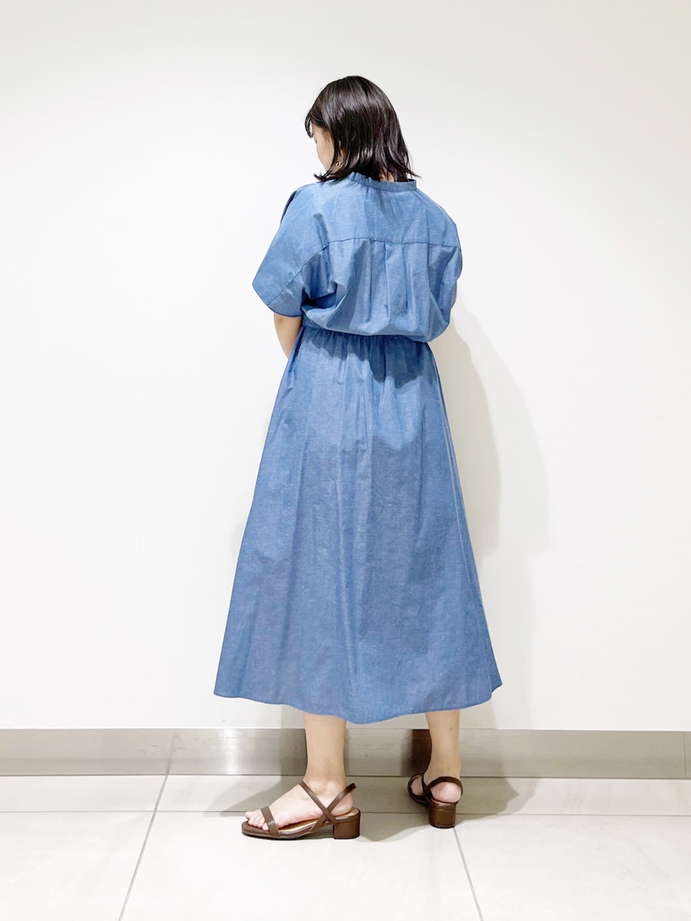 ブルー系のワンピース、ブラウン系のハンドバッグ、ブラウン系のサンダルを着用したレディースの夏コーディネートの5枚目の写真