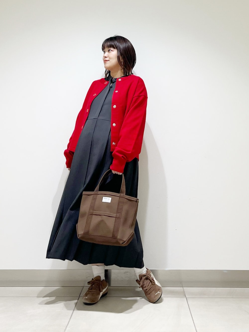 グレー系のワンピース、ブラウン系のトートバッグ、レッド系のカーディガン/ボレロを着用したレディースの秋コーディネートの4枚目の写真