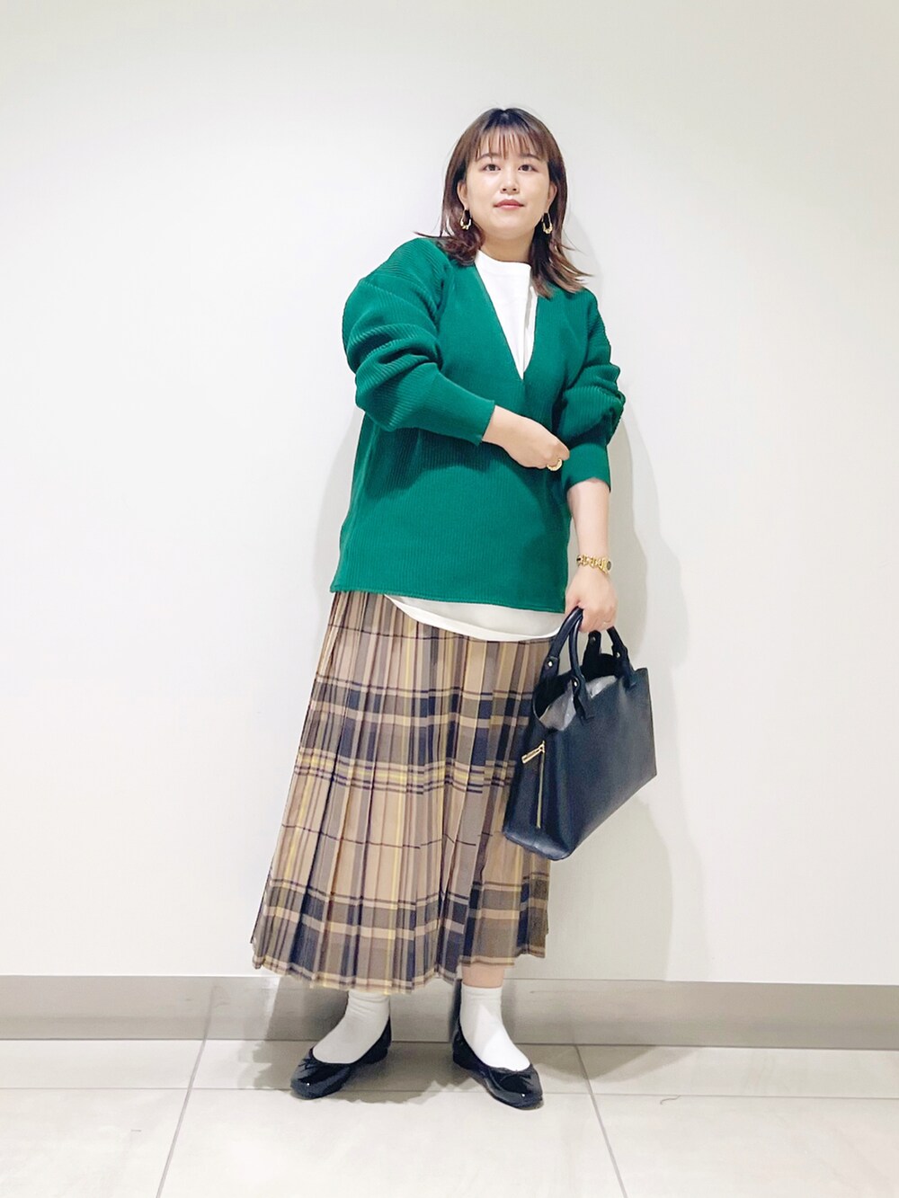 グリーン系のニット/セーター、ブラック系のトートバッグ、ベージュ系のスカートを着用したレディースの秋コーディネートの4枚目の写真