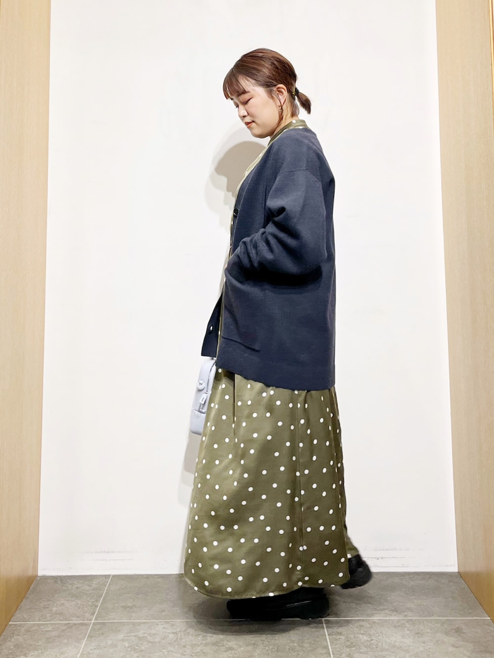 ブルー系のカーディガン/ボレロ、グリーン系のワンピース、ブルー系のハンドバッグを着用したレディースの冬コーディネートの3枚目の写真