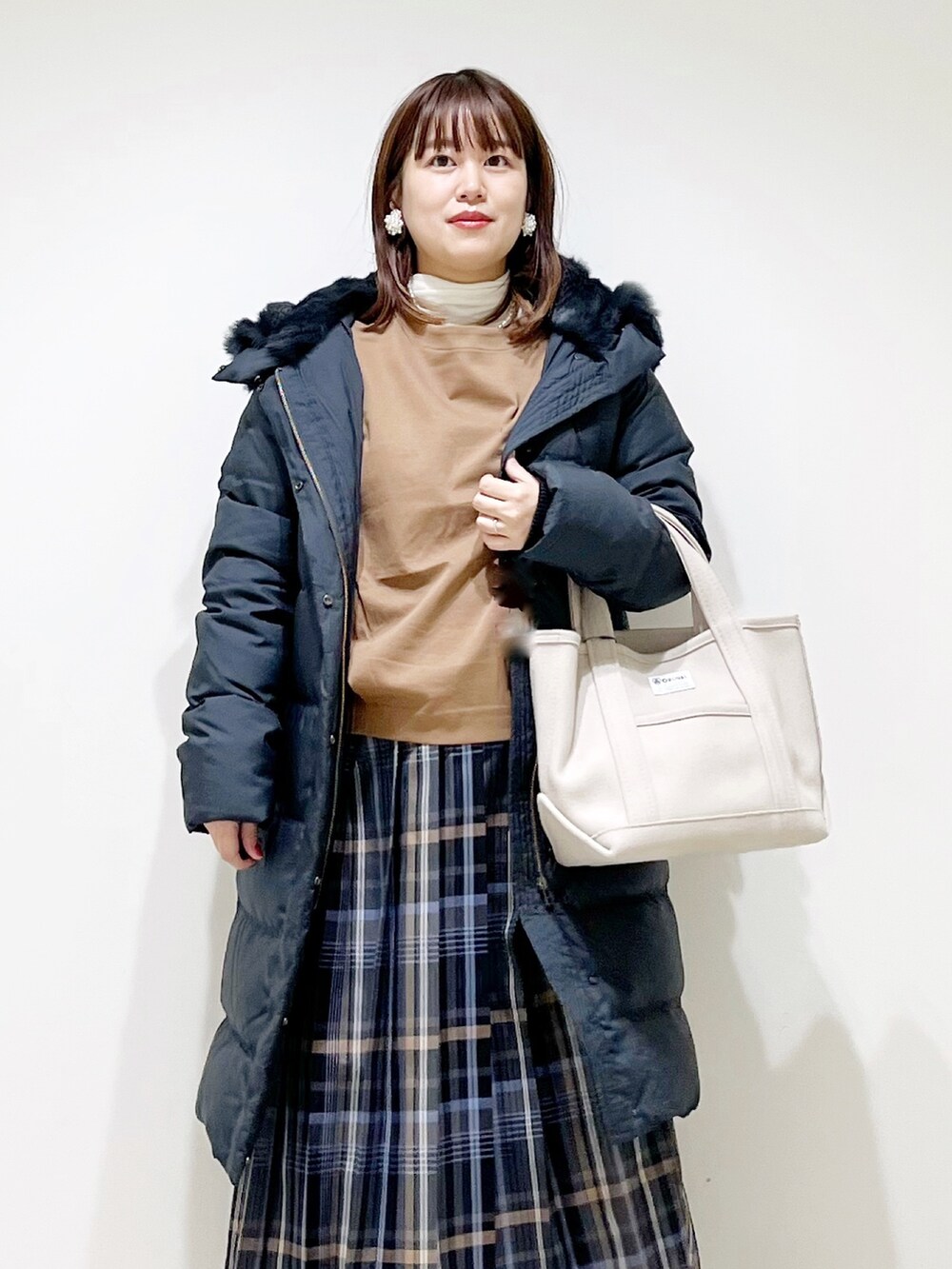 イエロー系のTシャツ/カットソー、ブラック系のダウンジャケット/コート、ブルー系のスカートを着用したレディースの秋コーディネートの6枚目の写真