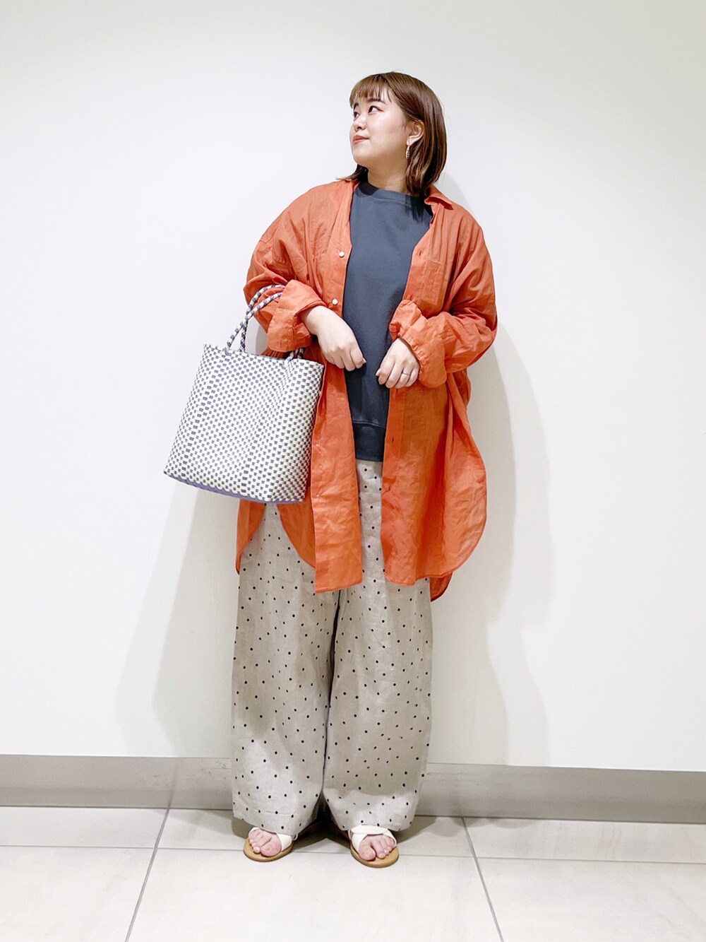 オレンジ系のシャツ/ブラウス、グリーン系のTシャツ/カットソー、パープル系のトートバッグを着用したレディースの春コーディネートの4枚目の写真