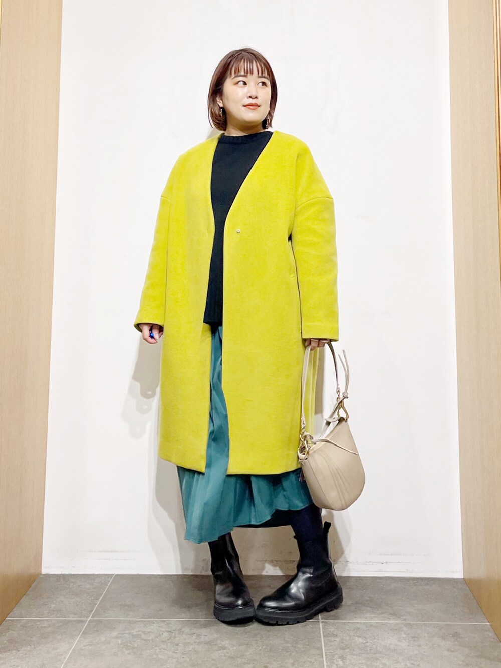 ブラック系のニット/セーター、イエロー系のその他アウター、グリーン系のスカートを着用したレディースの冬コーディネートの3枚目の写真