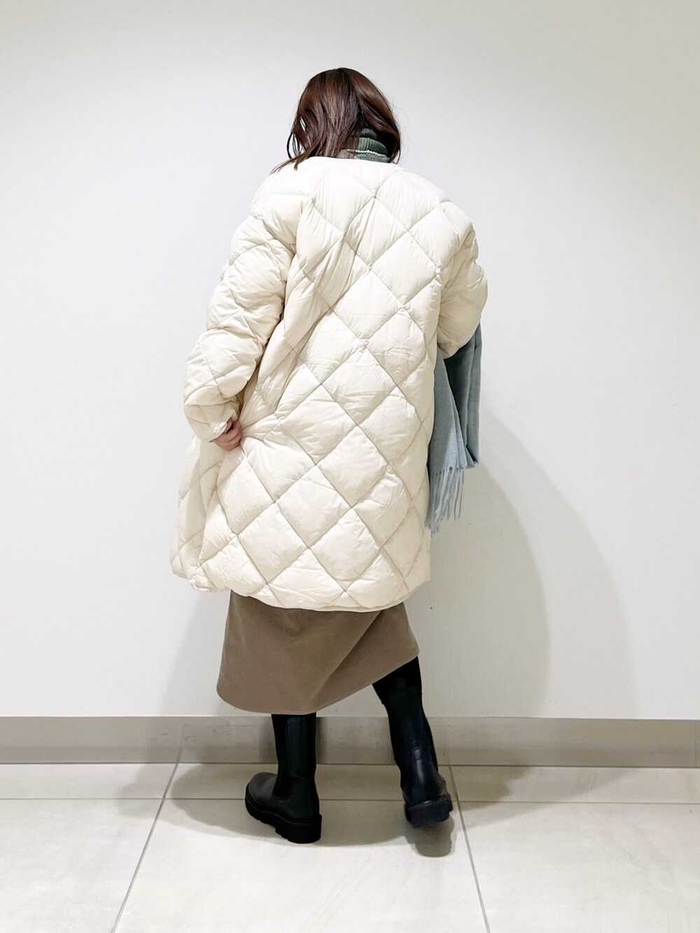 ベージュ系のワンピース、ホワイト系のダウンジャケット/コート、ブラック系のブーツを着用したレディースの冬コーディネートの6枚目の写真