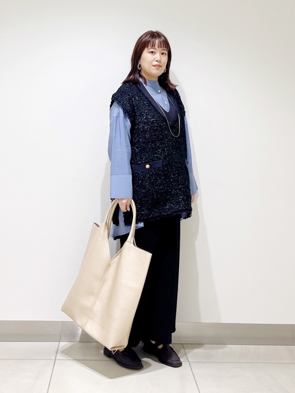 ブルー系のシャツ/ブラウス、ブラック系のスカート、ゴールド系のトートバッグを着用したレディースの秋コーディネートの7枚目の写真