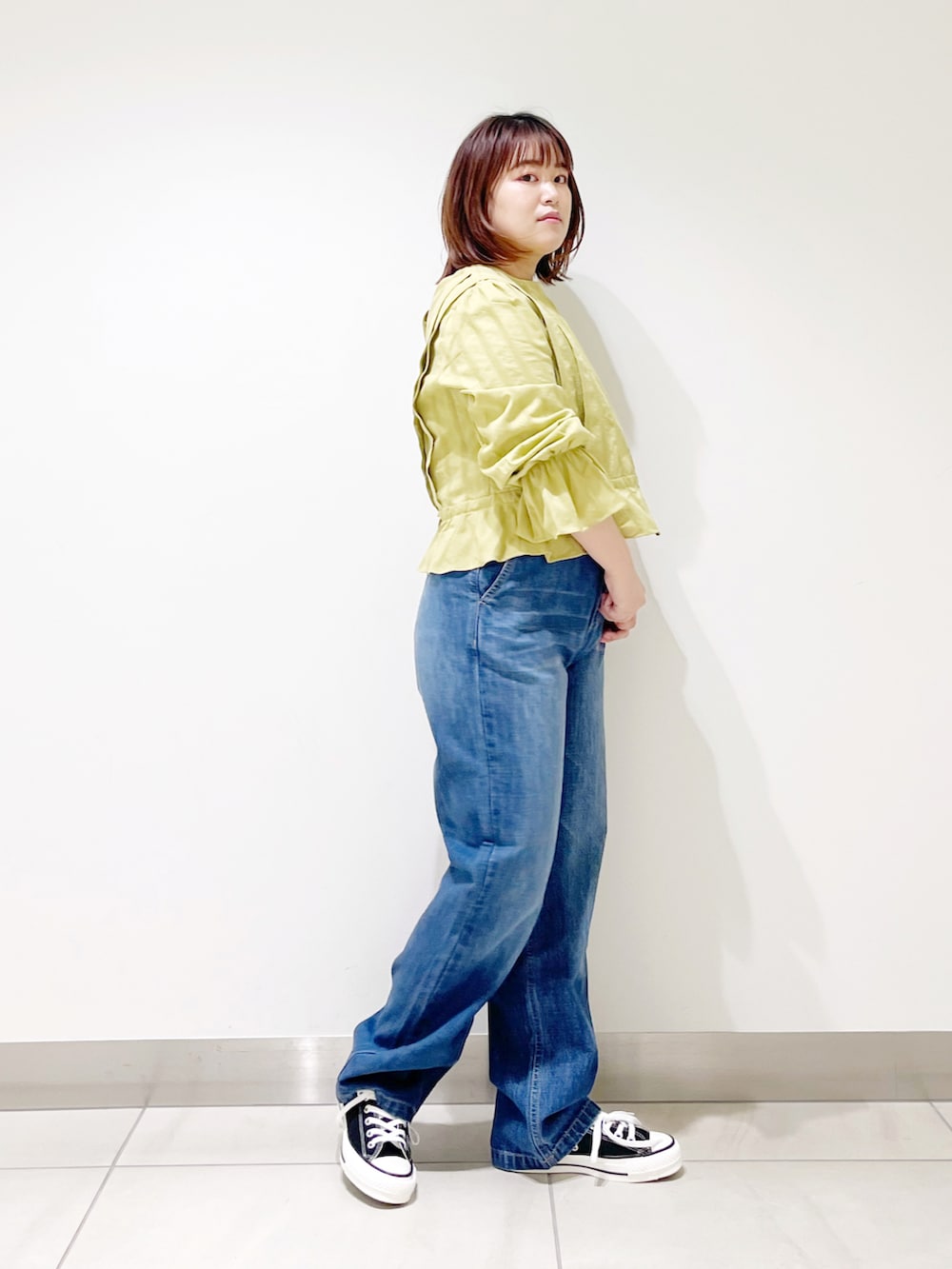 グリーン系のシャツ/ブラウス、ブルー系のデニムパンツ、ブラック系のスニーカーを着用したレディースの春コーディネートの2枚目の写真