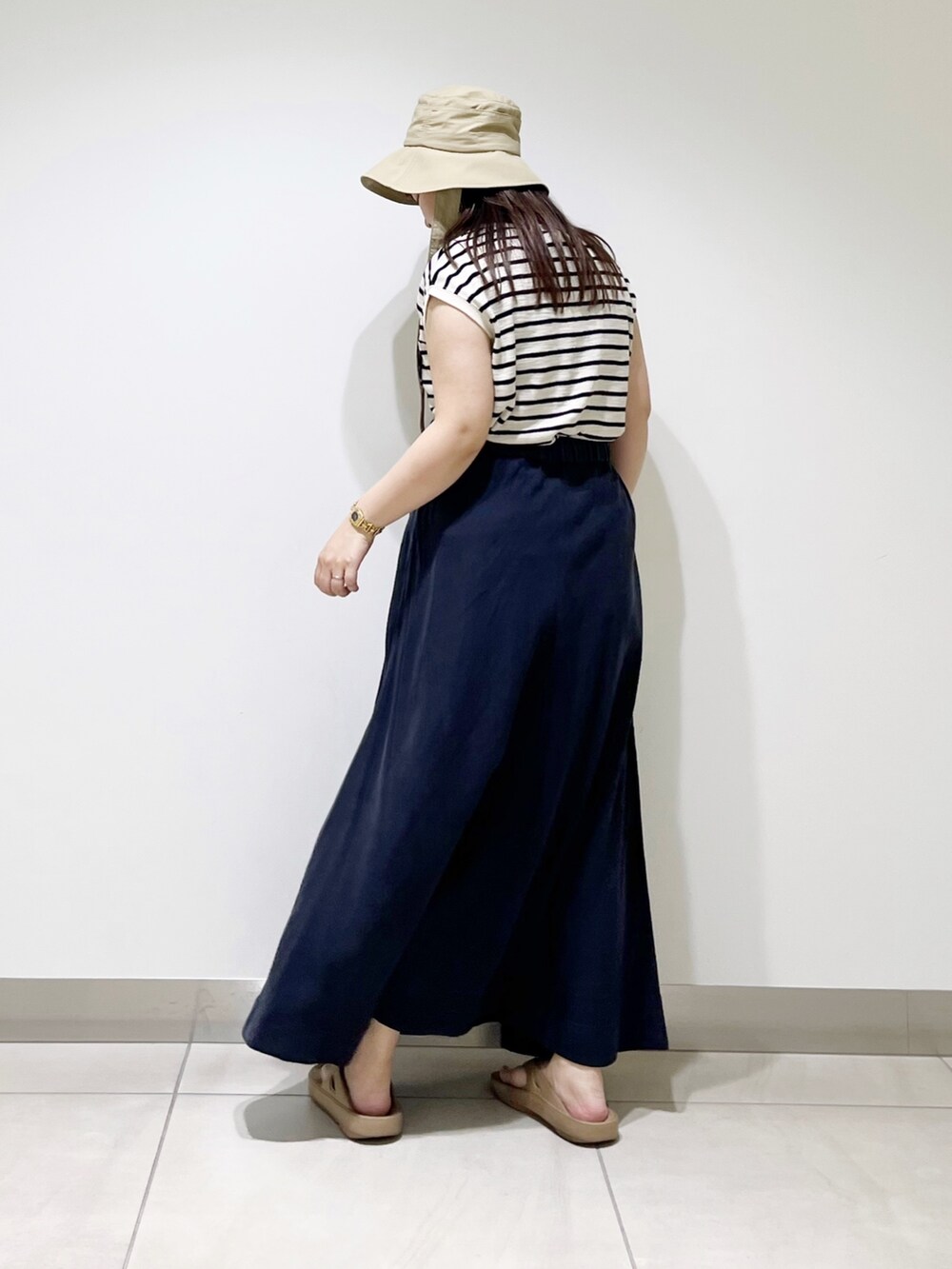 ベージュ系のTシャツ/カットソー、ブルー系のスカート、ベージュ系のサンダルを着用したレディースの夏コーディネートの7枚目の写真