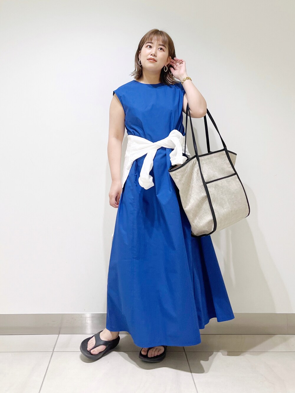 ブルー系のワンピース、ブラック系のトートバッグ、ブラック系のサンダルを着用したレディースの春コーディネートの2枚目の写真