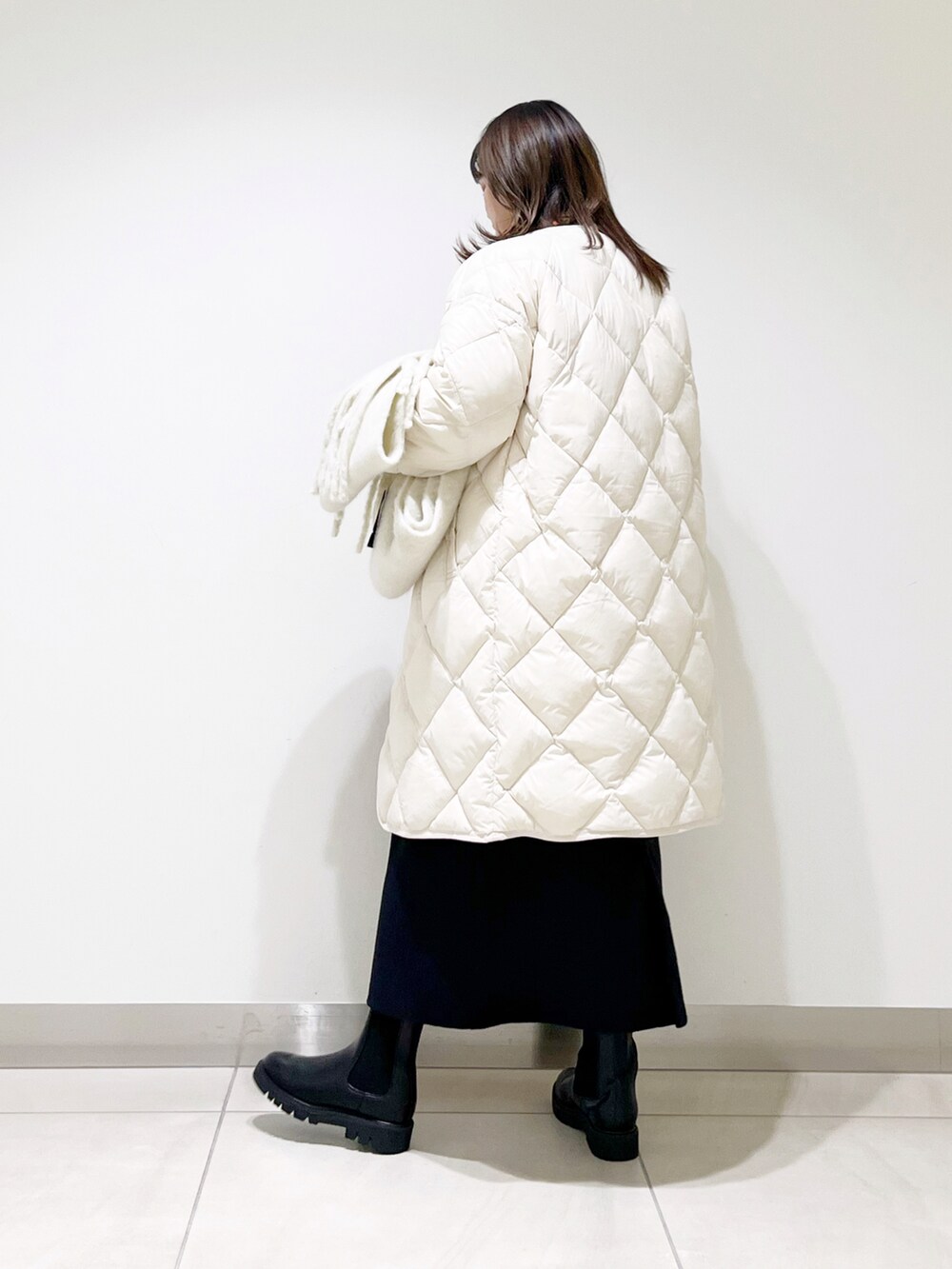 ベージュ系のダウンジャケット/コート、オレンジ系のニット/セーター、ブルー系のスカートを着用したレディースの秋コーディネートの3枚目の写真