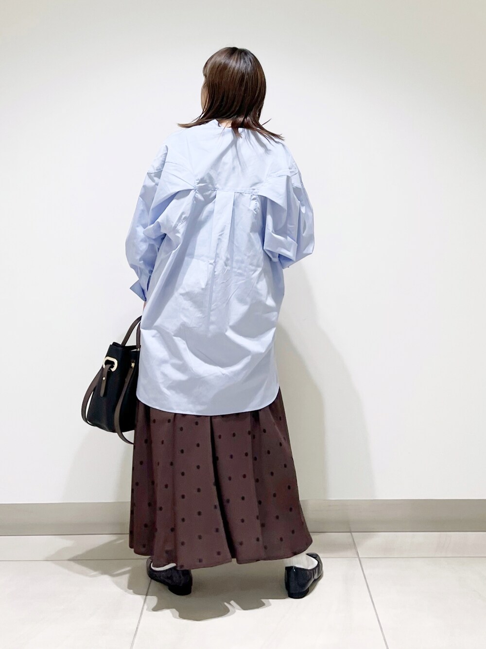 パープル系のワンピース、ブラック系のトートバッグ、ブラウン系のスカートを着用したレディースの秋コーディネートの4枚目の写真