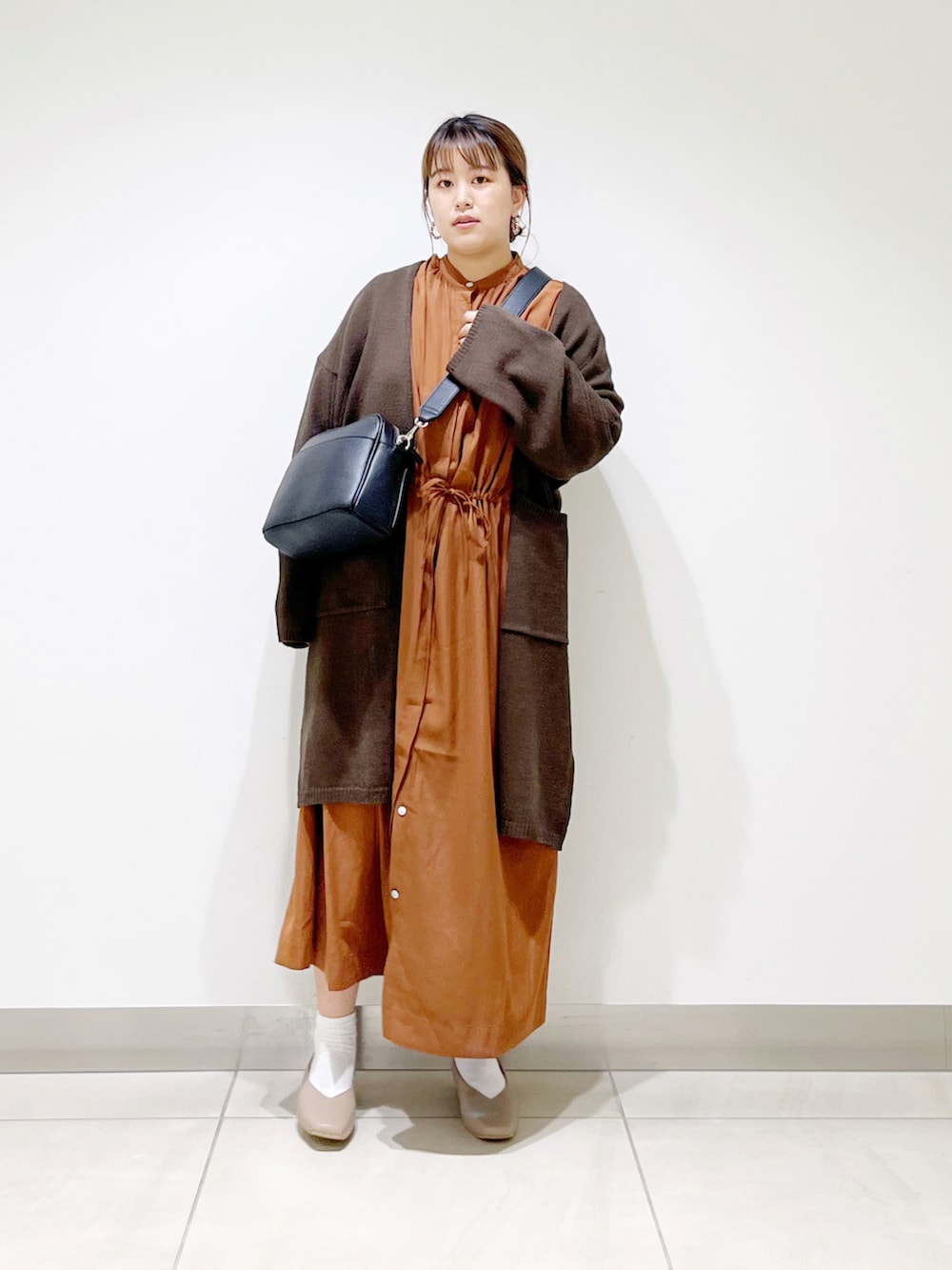 ブラウン系のカーディガン/ボレロ、イエロー系のワンピース、ブラック系のショルダーバッグを着用したレディースの秋コーディネートの3枚目の写真