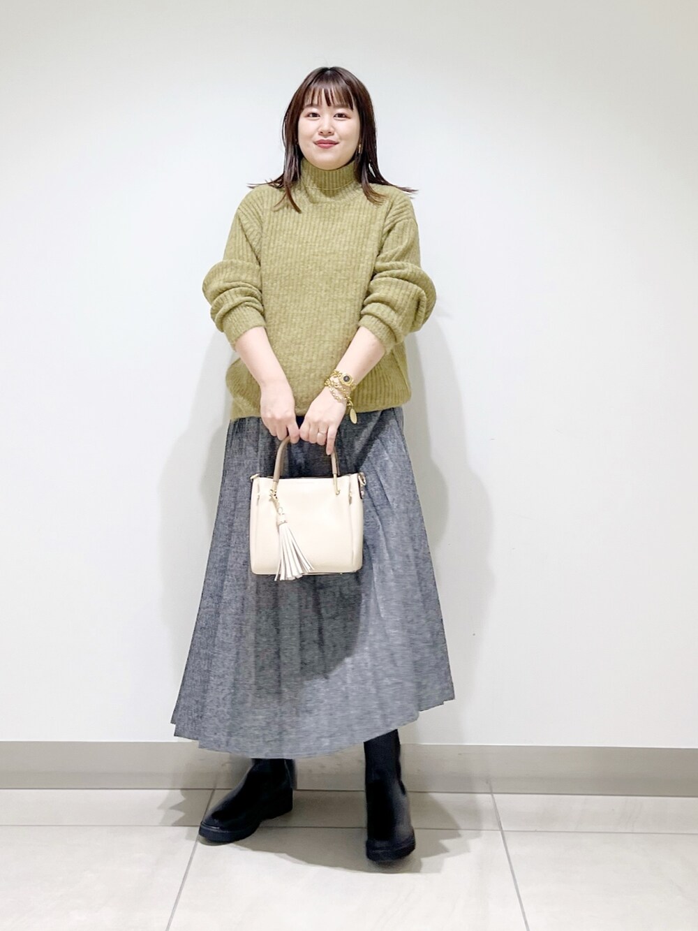 グリーン系のニット/セーター、ブルー系のスカート、ホワイト系のトートバッグを着用したレディースの冬コーディネートの5枚目の写真