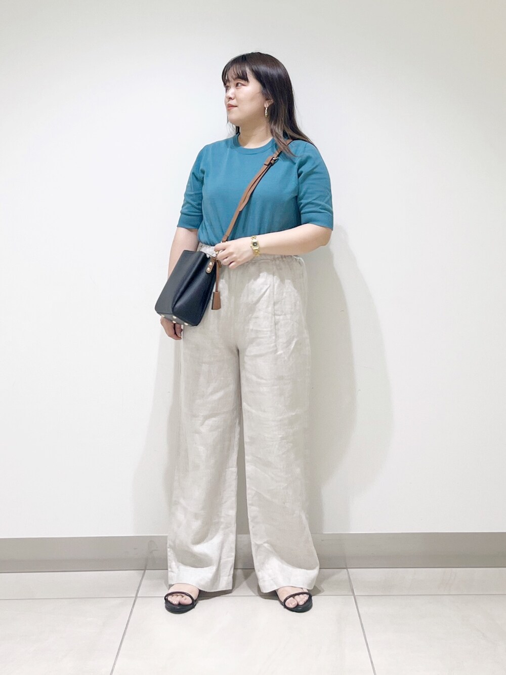 ブルー系のニット/セーター、ベージュ系のその他パンツ、ブラック系のショルダーバッグを着用したレディースの春コーディネートの3枚目の写真