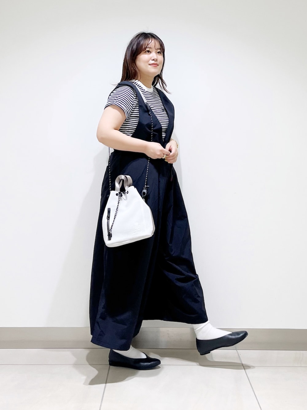 ブラック系のサロペット/オーバーオール、グレー系のTシャツ/カットソー、ホワイト系のショルダーバッグを着用したレディースの春コーディネートの2枚目の写真