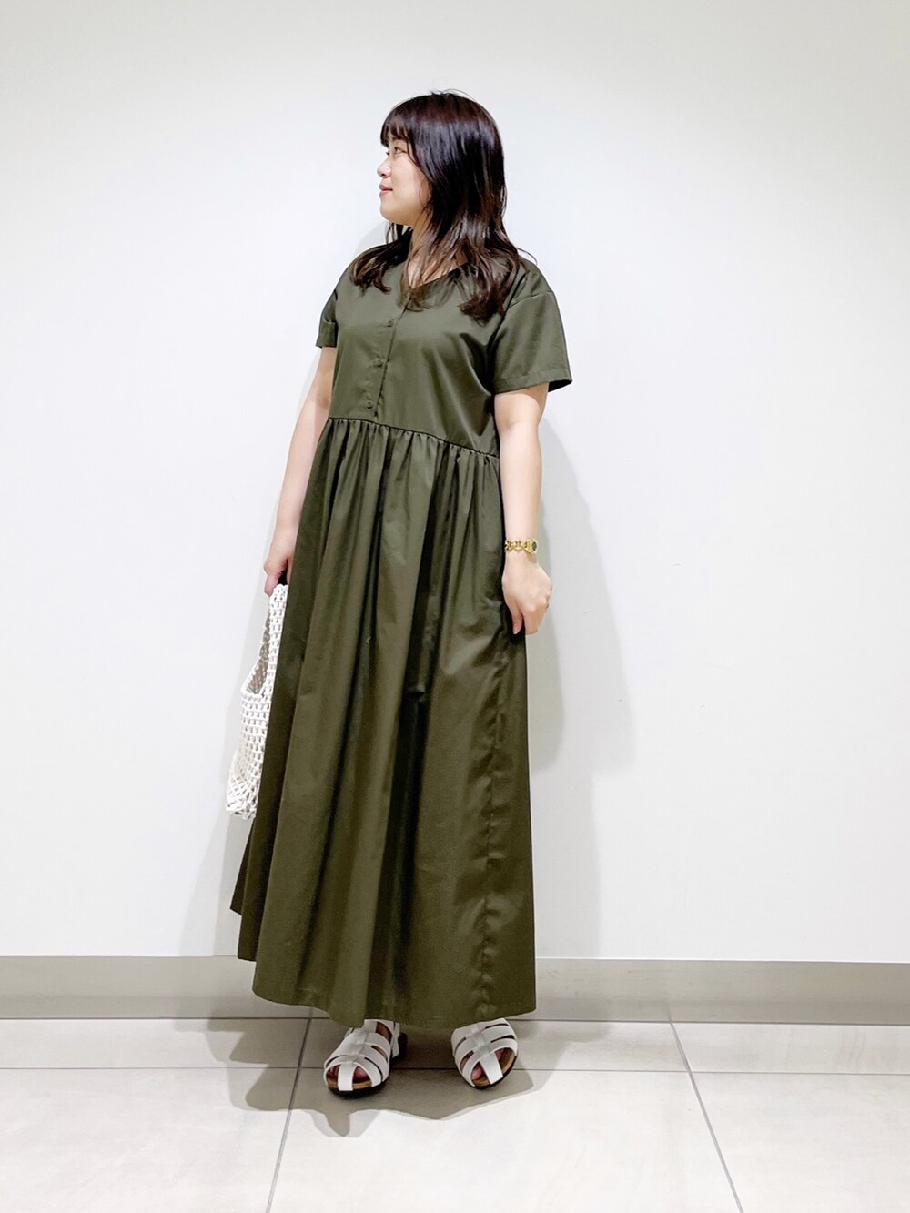 グリーン系のワンピース、ホワイト系のバッグ、ホワイト系のシューズを着用したレディースの春コーディネートの3枚目の写真