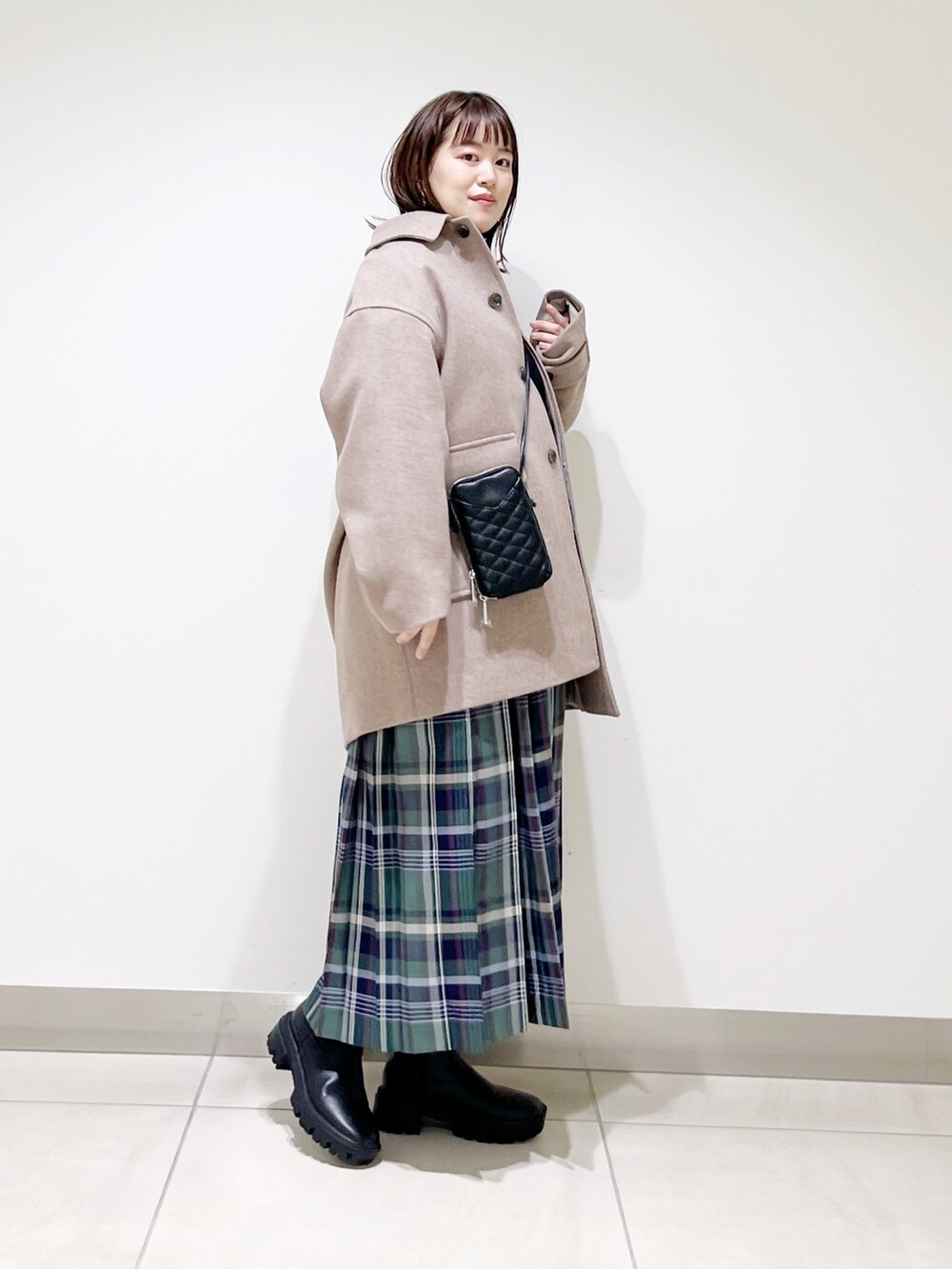 ブラウン系のその他アウター、ブラック系のニット/セーター、グリーン系のスカートを着用したレディースの秋コーディネートの4枚目の写真