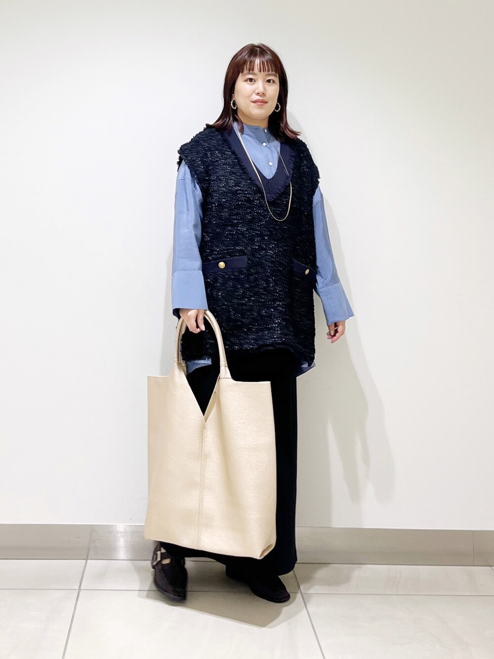 ブルー系のシャツ/ブラウス、ブラック系のスカート、ゴールド系のトートバッグを着用したレディースの秋コーディネートの5枚目の写真