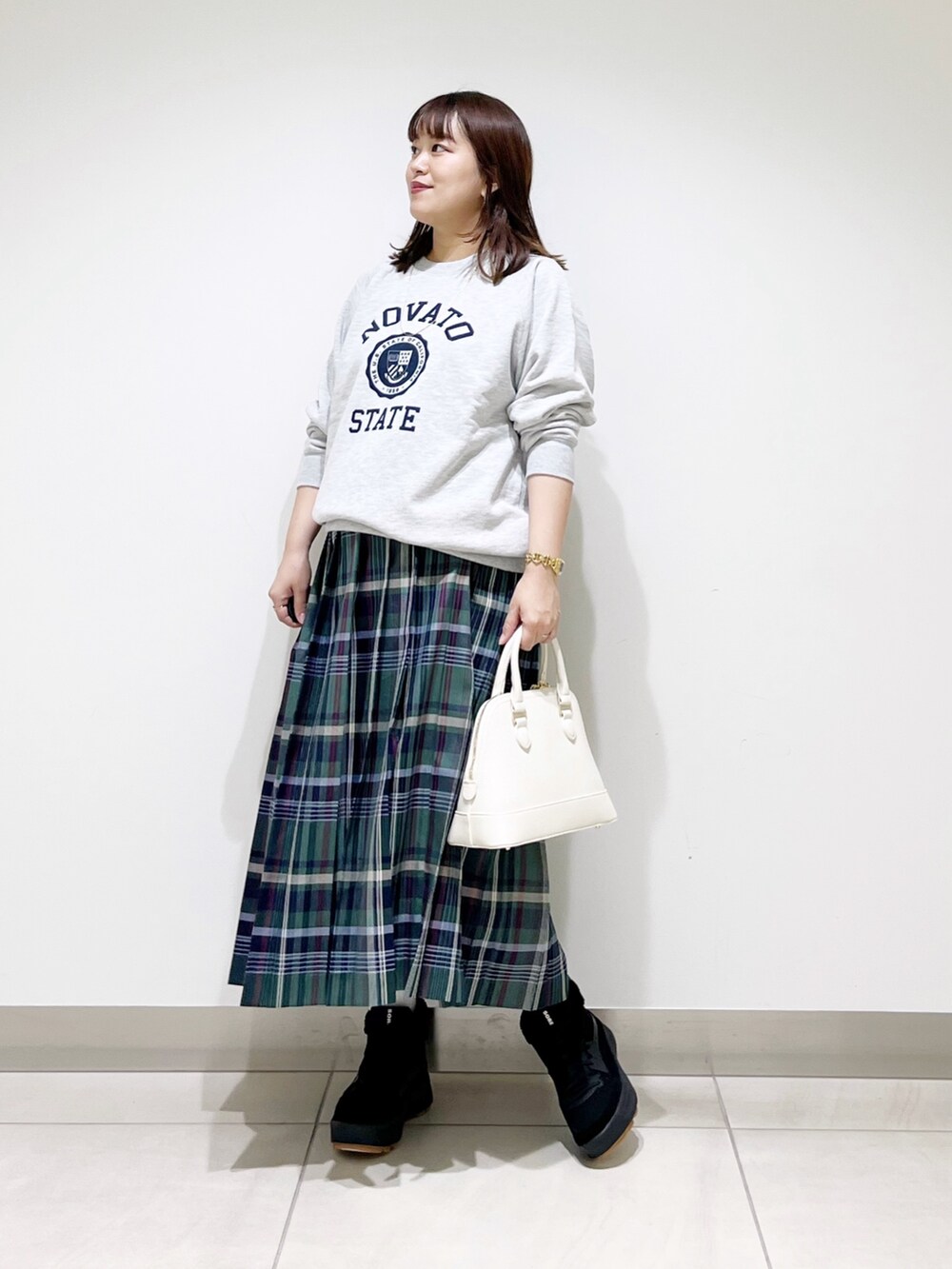 グリーン系のスカート、グレー系のスウェット、ホワイト系のショルダーバッグを着用したレディースの冬コーディネートの4枚目の写真