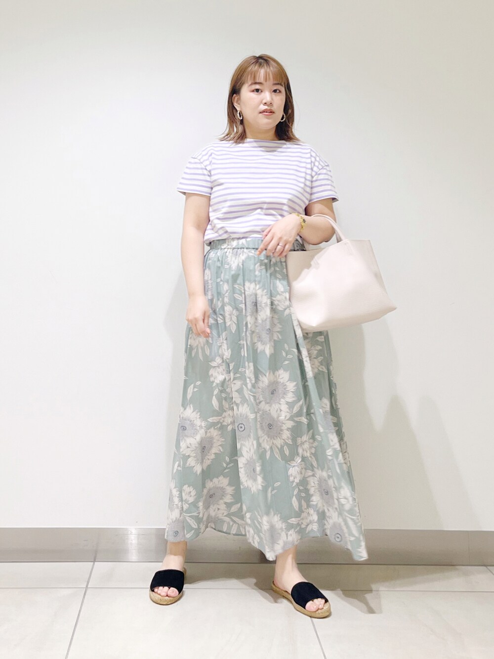 グリーン系のスカート、パープル系のTシャツ/カットソー、ホワイト系のトートバッグを着用したレディースの春コーディネートの2枚目の写真